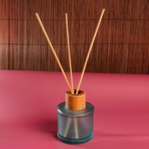 Aromatherapy diffuser with bamboo sticks on a pink surface and bamboo background